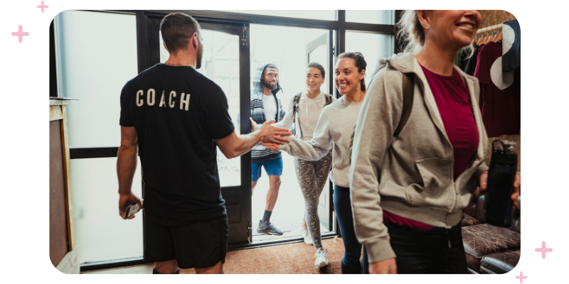 A coach greeting each member as they arrive to class at the gym