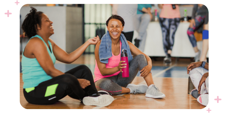 Two women laughing as they take a break from an intense workout class