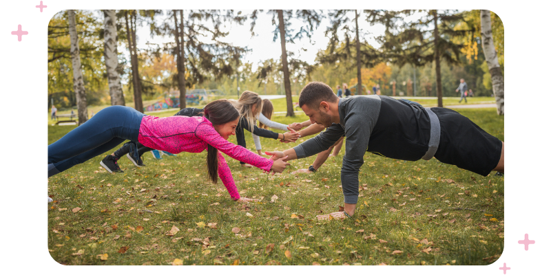 An exercise class in an outdoor bootcamp in a park with autumn leaves in the background