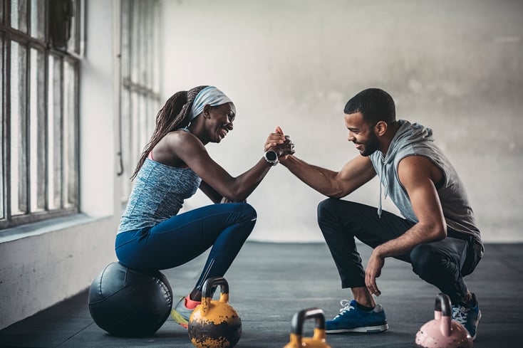 A client high-fiving with their fitness instructor in a gym or studio