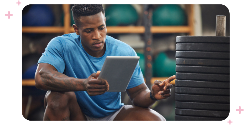 Gym owner holding a tablet while counting weight plates.