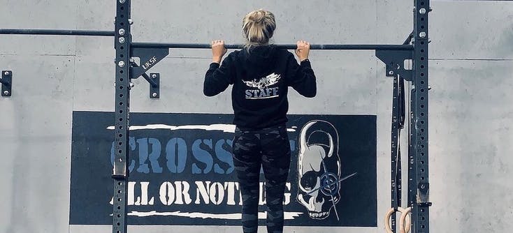 A CrossFit box member doing pull-ups in a CrossFit gym