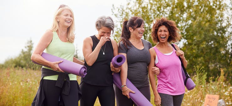 Women holding yoga mats and laughing.
