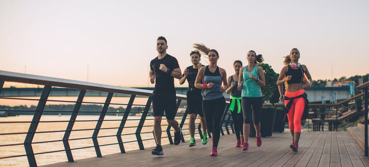 group of people running outside at sunset