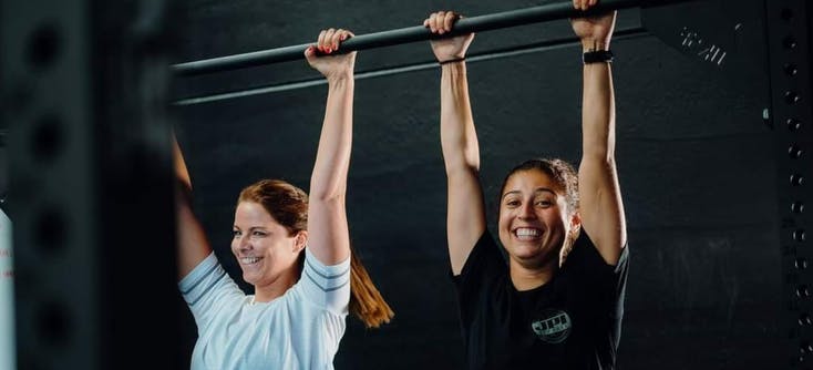 two girls at the gym holding onto a bar