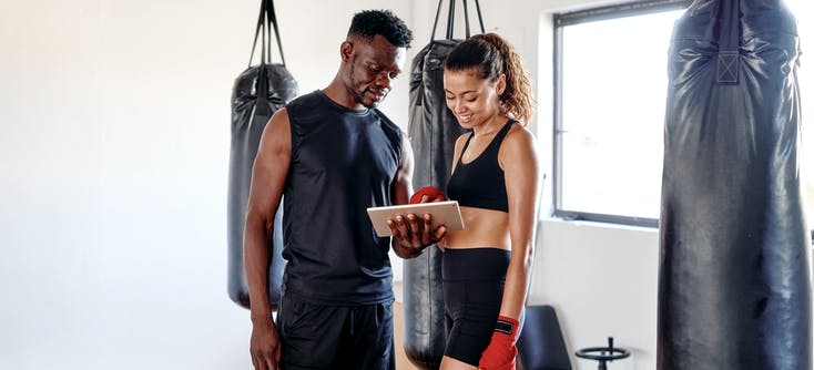 gym owner showing a customer how to use their tablet