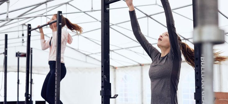 Two CrossFit box members doing pull ups.