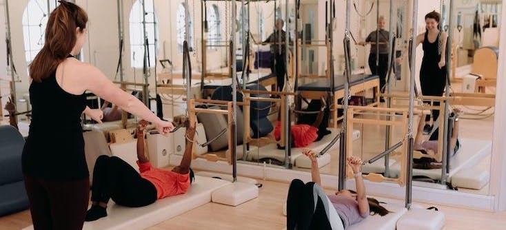 An instructor leading a Pilates class in their Pilates studio