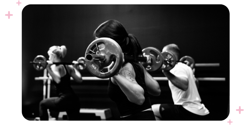 People working out with barbells at the gym.