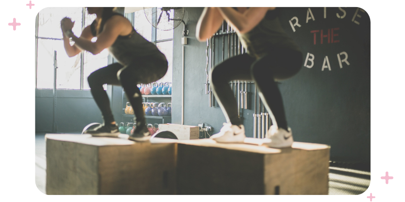 A functional fitness session; two women are jumping onto boxes.