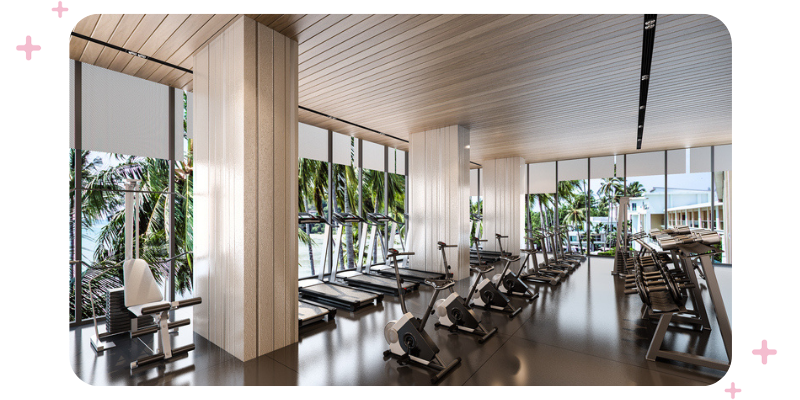 A really nice gym with a lot of equipment and big windows overlooking the beach and palm trees.