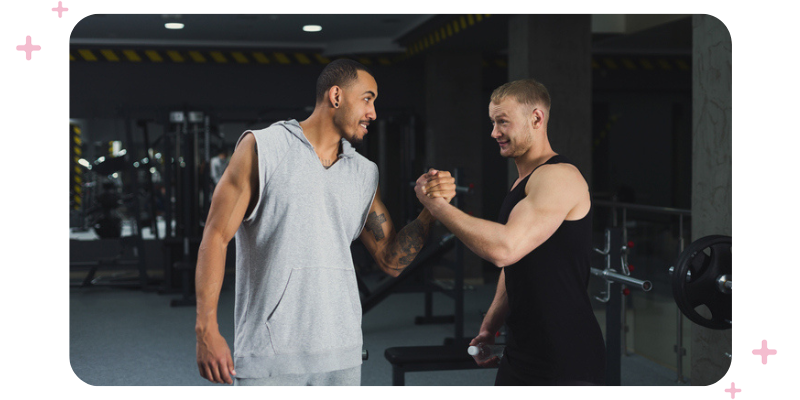 Two men in workout clothes fist bumping at the gym.