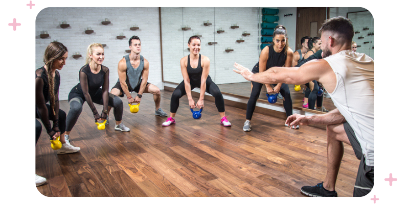 People at the gym doing a group kettlebells class.