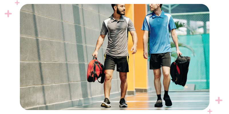 Two men in workout clothes walking into a fitness facility.
