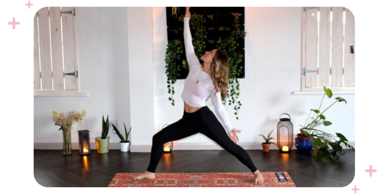 A woman doing yoga in a studio; there are lamps and plants on the floor.