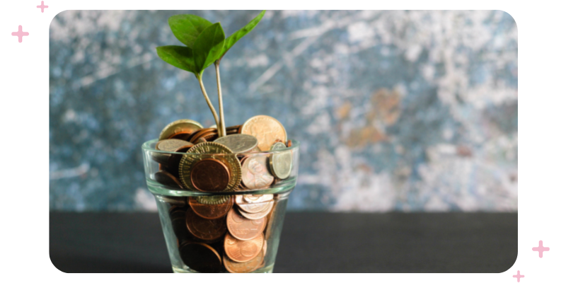 A clear flower pot filled with coins, with a plant growing in it.