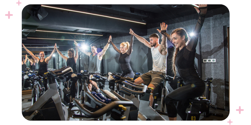 Spin class at a gym with people high-fiving.