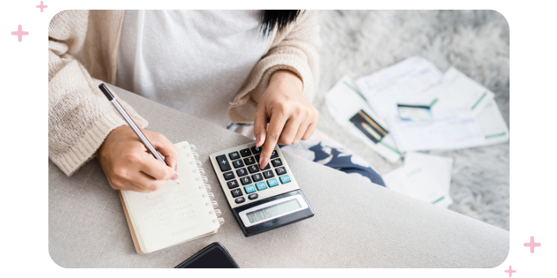 A woman writing in a notebook, with a calculator next to the notebook..