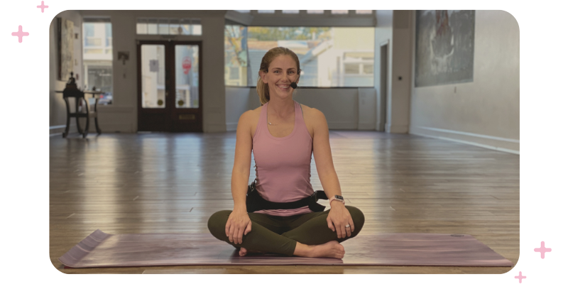 A yoga teacher sitting on the floor of her studio.